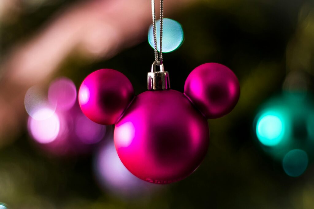 Close-up of a pink Mickey Mouse-shaped ornament hanging on a Christmas tree.