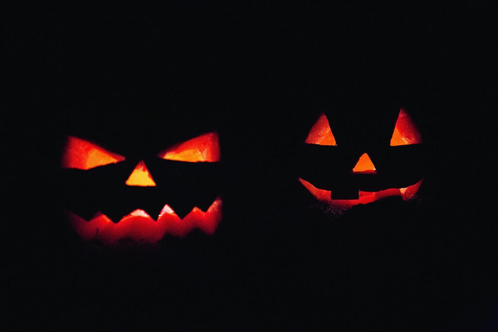 Two illuminated jack-o'-lanterns in dark, creating an eerie Halloween atmosphere.